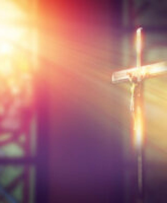 crucifix, jesus on the cross in church with ray of light from stained glass