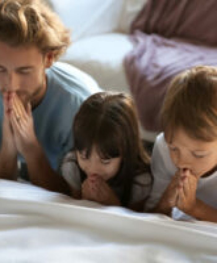 Family praying near bed at home